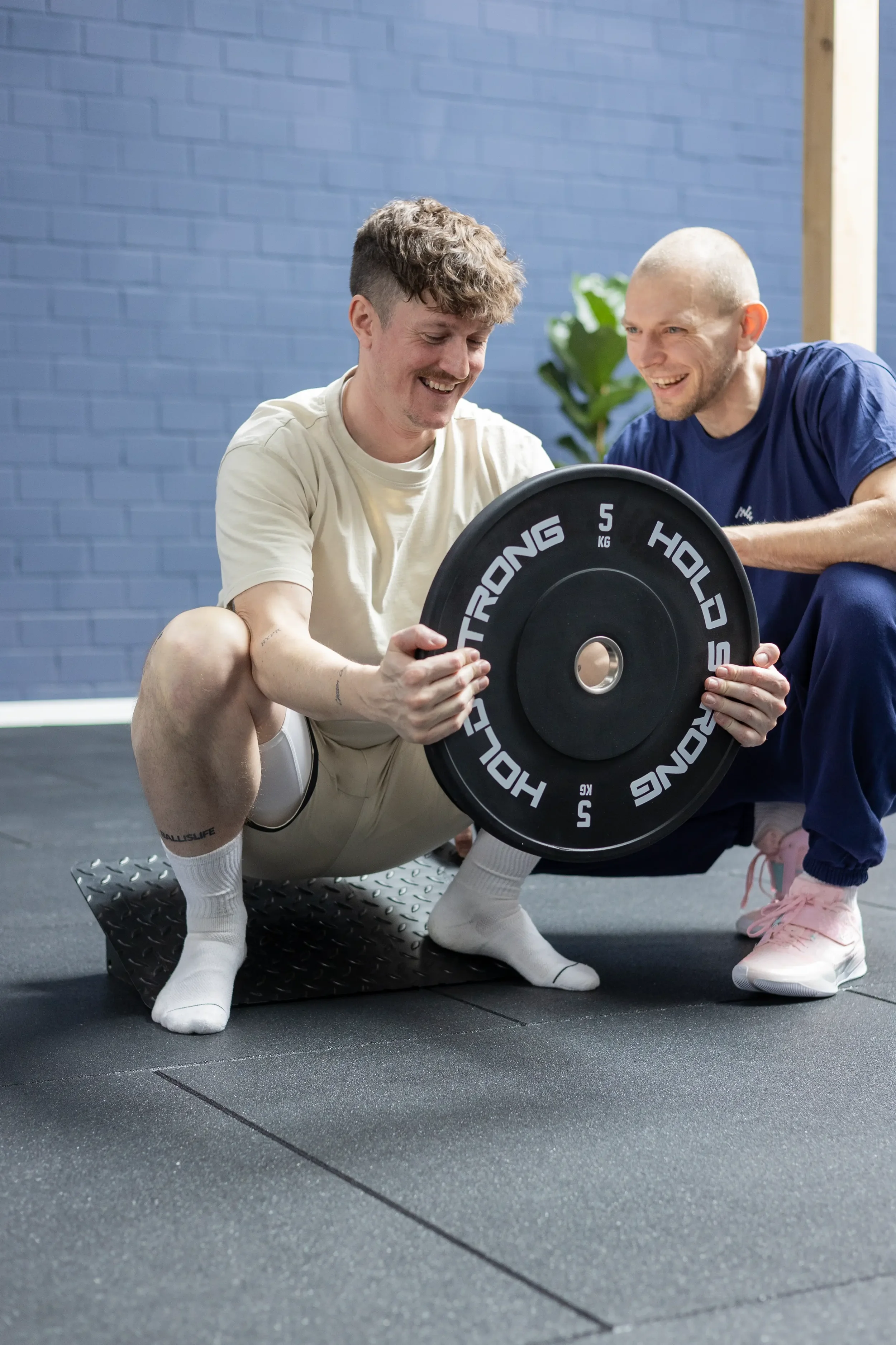 Ein Physiotherapeut der Neuen Freiheit in Bayreuth und ein Patient bei der aktiven Physiotherapie. Der Patient macht einen Deepsquat.