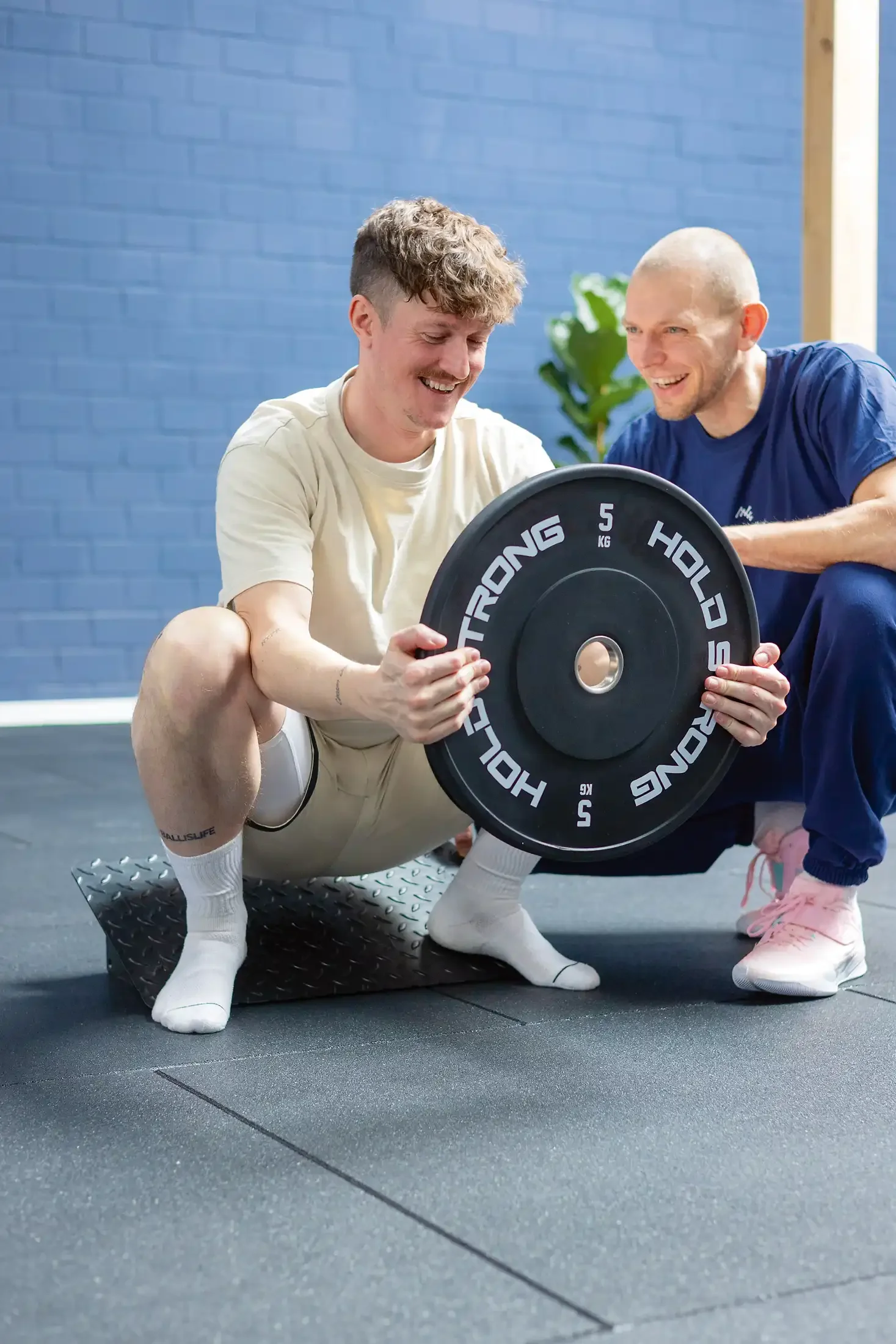 Ein Physiotherapeut von Neue Freiheit Physio & Fitness macht Kniebeuge-Übung mit einem Patienten.