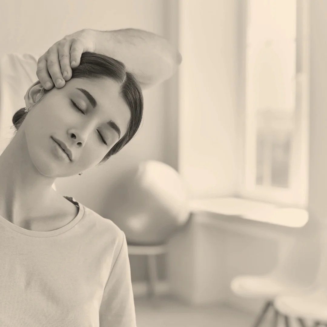 Woman receiving neck therapy with therapist's hand on her head, indoors.