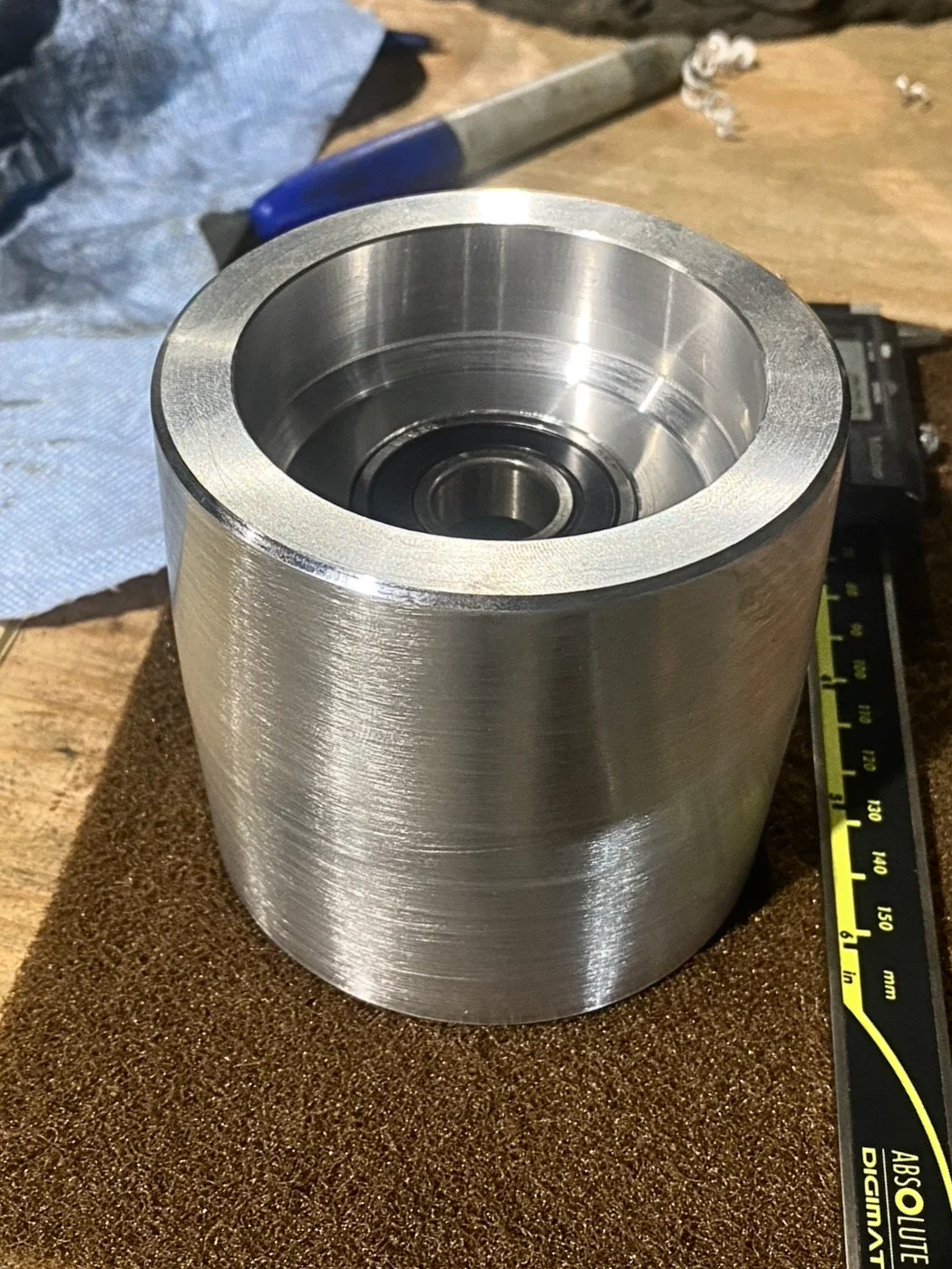 Custom machined aluminum pulley manufactured for a belt sander to improve belt tracking and machine performance.