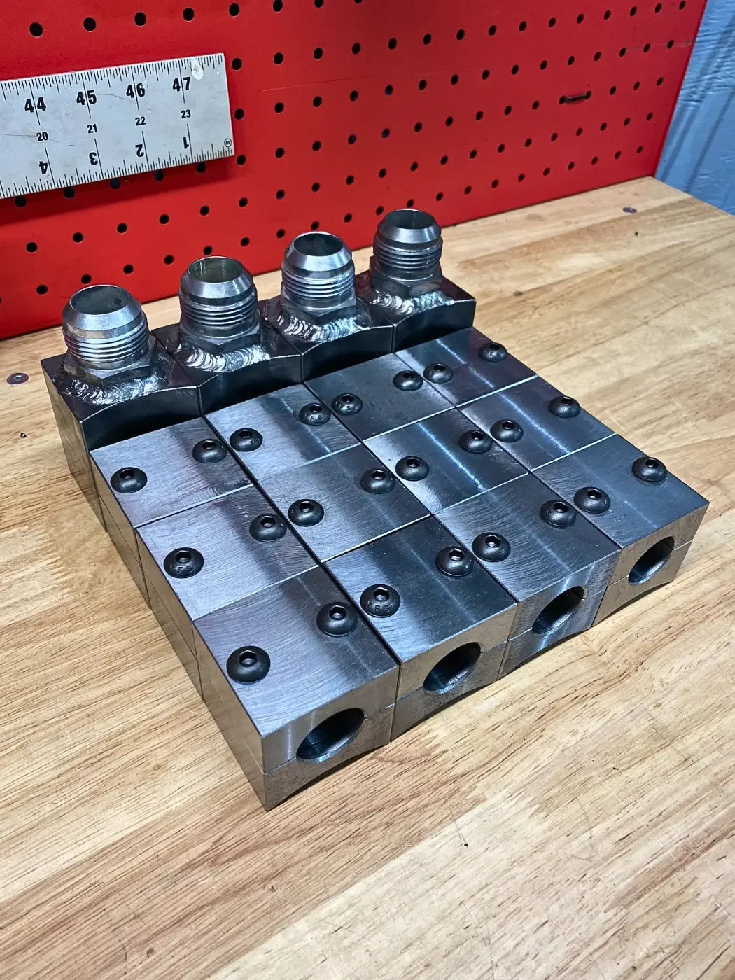 Custom hydraulic line tie down blocks and weld-on fittings used to secure, route, and protect hydraulic lines