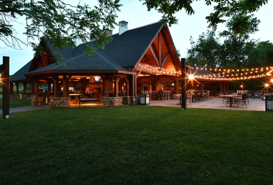 A wooden pavilion with strings of party lights strung over a patio