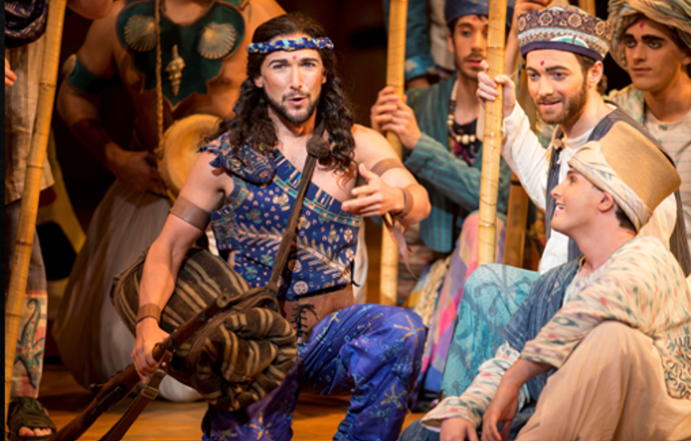 Aaron Blake performing a scene in The Pearl Fishers, wearing a blue costume and holding a staff.