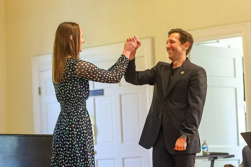 Aaron Blake and a young student celebrating with a high-five in an indoor setting.