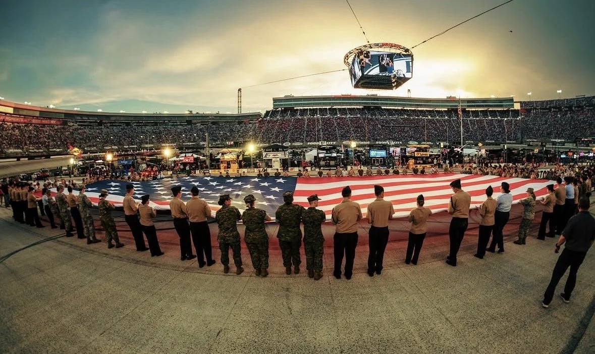 A group of veterans spreading out a large American flag in the infield of Bristol Motor Speedway