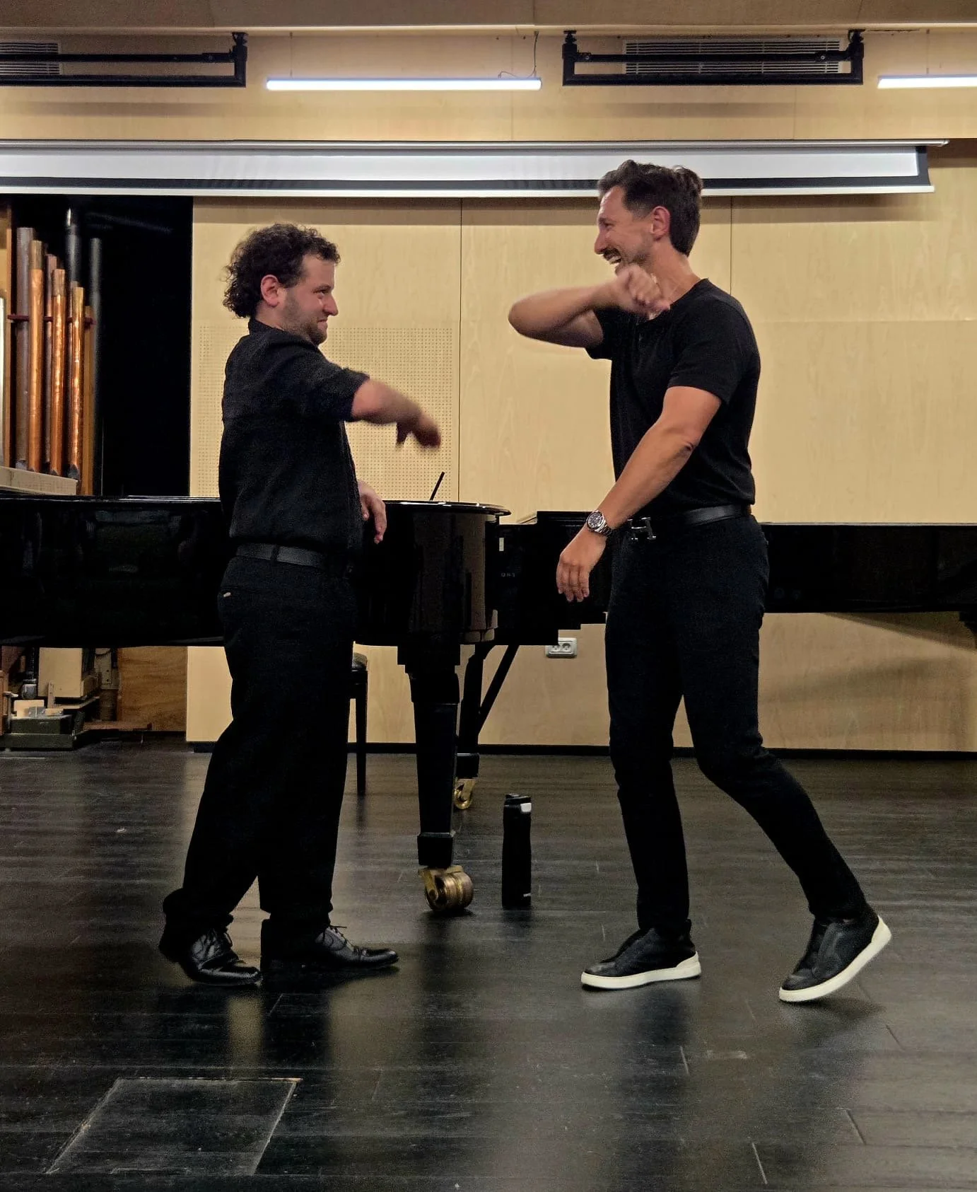 Aaron Blake and a student high-five in front of a grand piano