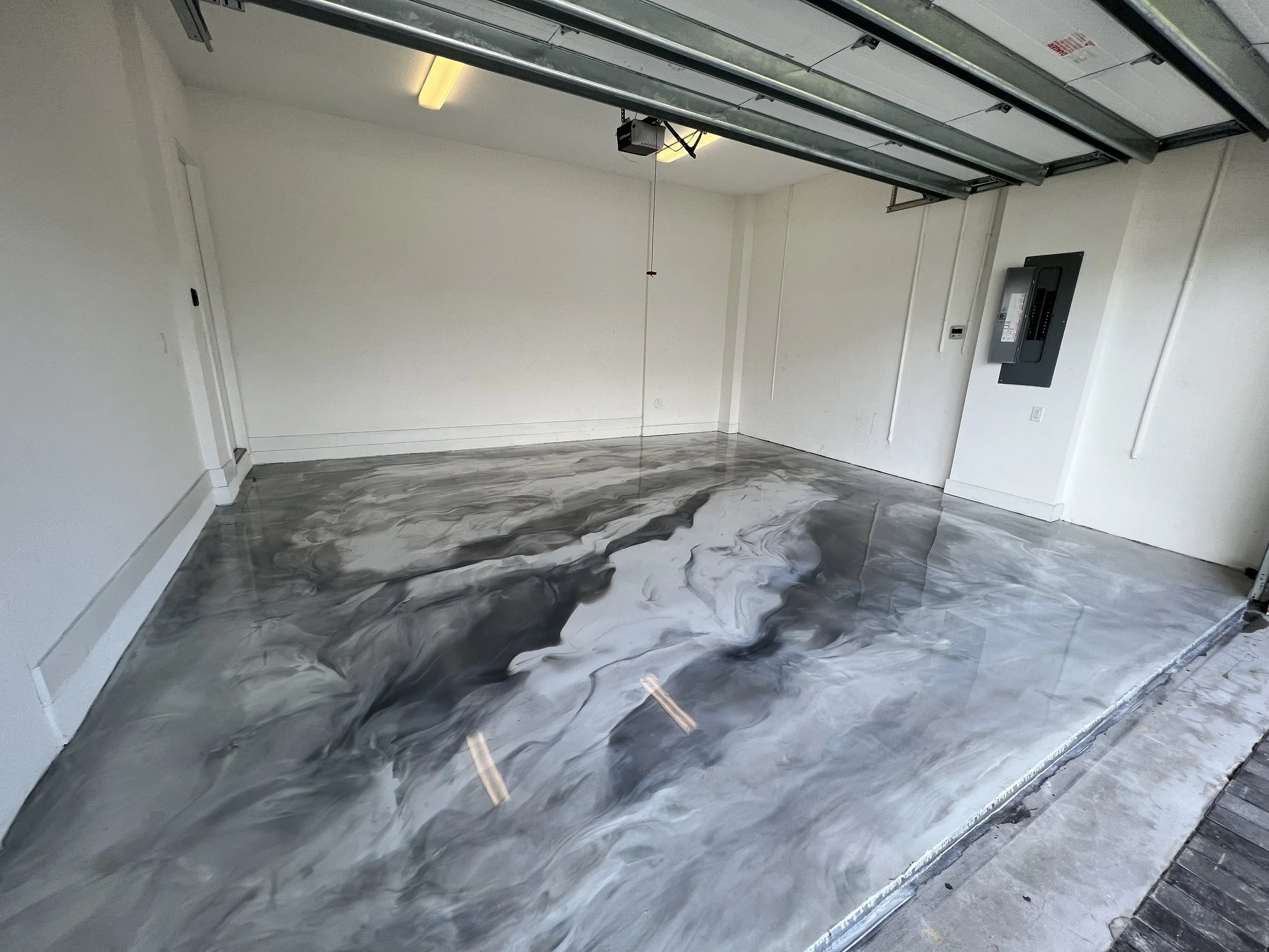 Empty garage with a polished concrete epoxy floor featuring black, white, and gray marble-like swirl patterns.