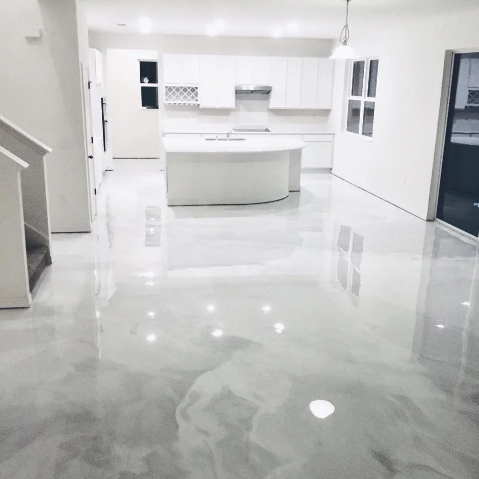 Refinished white kitchen with glossy floor, white cabinets, and a curved kitchen island.