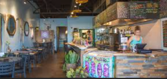 Interior of a cozy restaurant or cafe with tables, chairs, and a counter area with a menu board.