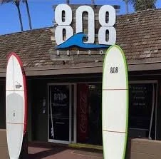 A storefront with a large sign displaying '808' and two surfboards standing outside.