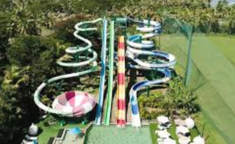 Water park with multiple twisting water slides surrounded by greenery and lounge chairs.