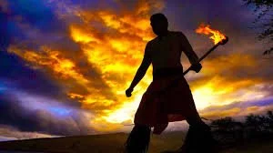 Person holding a flaming torch at sunset, silhouetted against a colorful sky.
