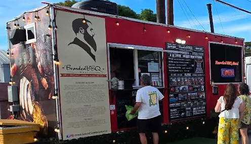 A food truck with a logo of a chef in a hat, serving customers. The truck displays a menu board and has an illuminated 'Open' sign.