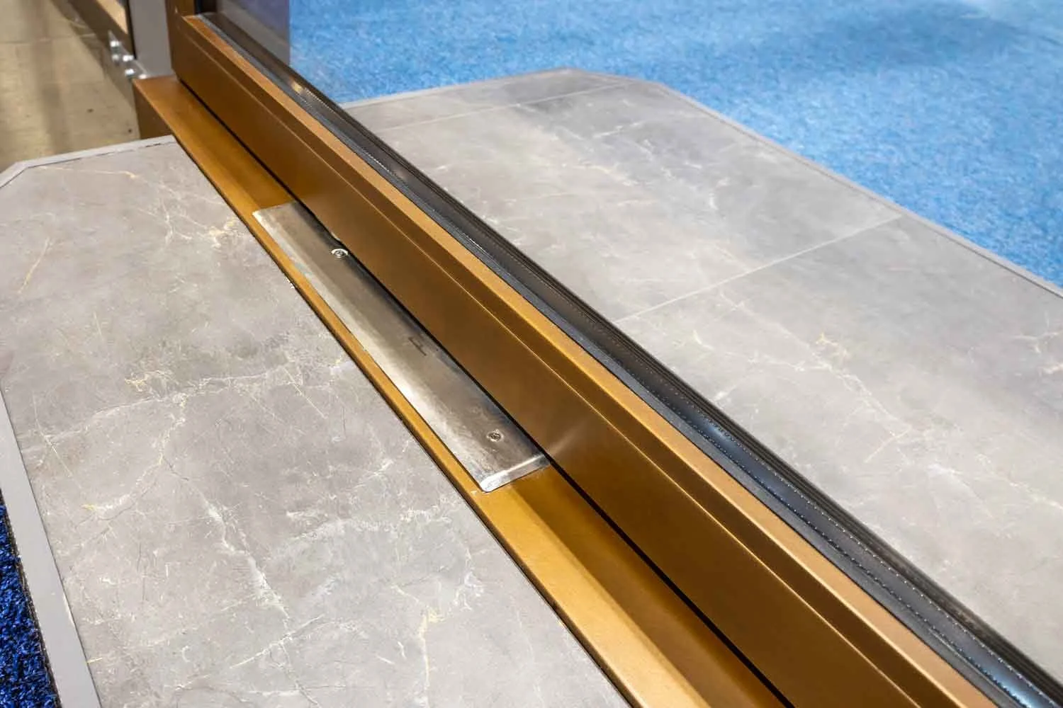 Close-up of a steel-framed pivot door featuring a brass-colored track.