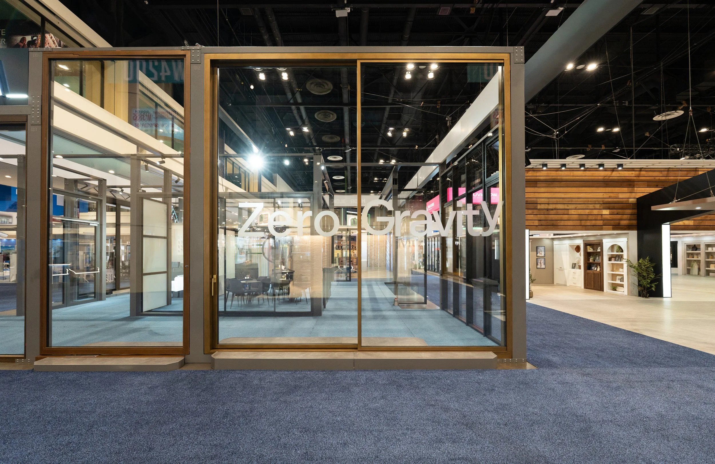 Tall bronze-framed sliding glass door with the words "Zero Gravity" written on it, showing an interior with chairs, tables, and modern decorations inside an indoor commercial space.