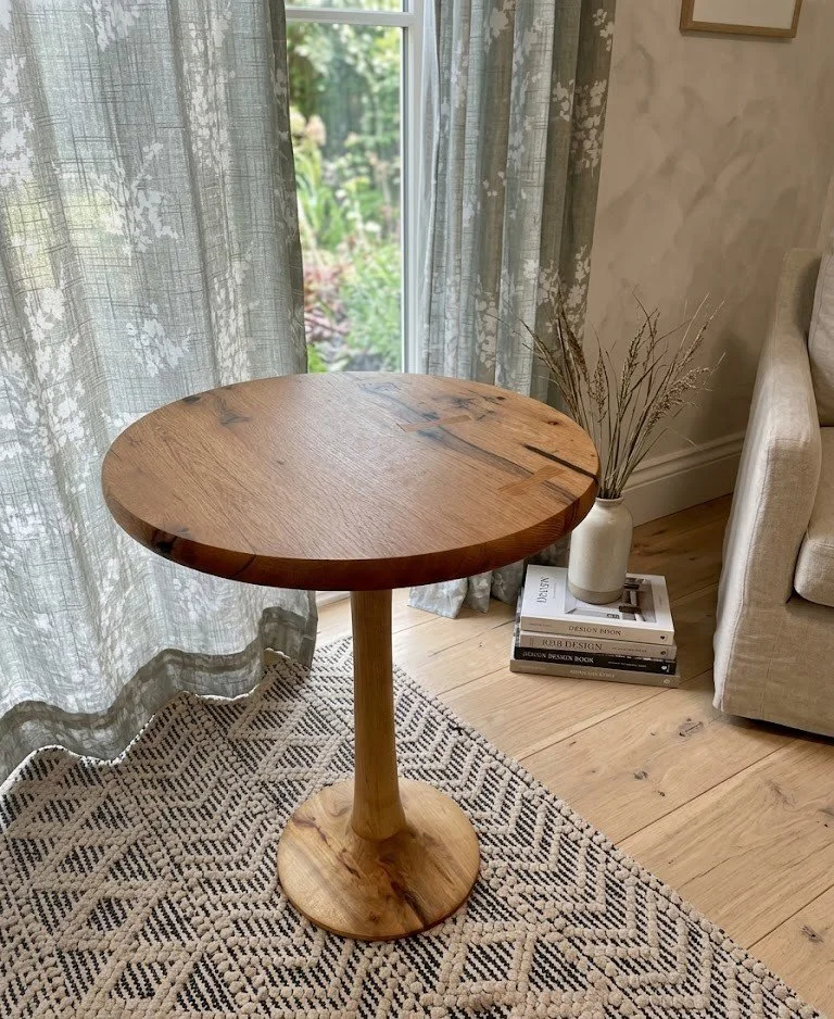Hand sculpted pedestal base round rustic oak wood side table with bowtie inlays. 