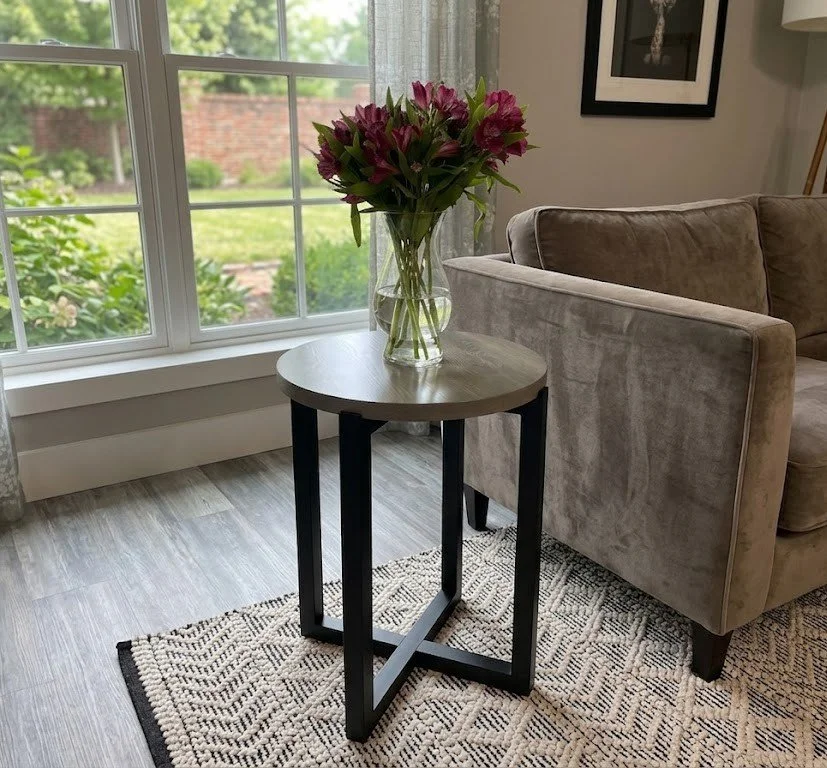 Modern round oak side table with black painted cross leg base. 