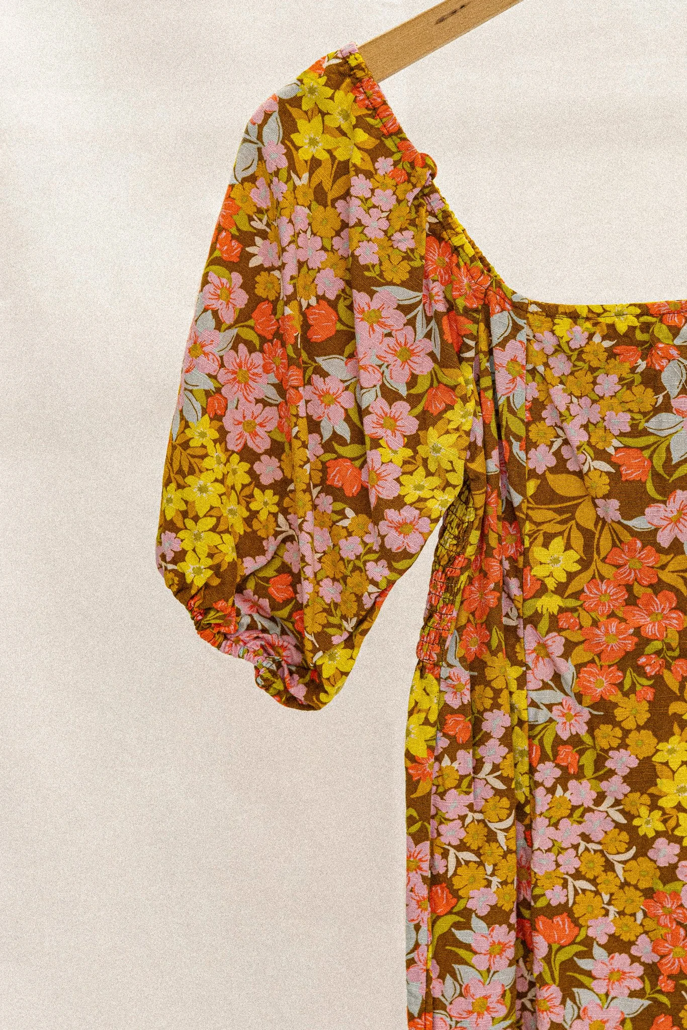 Robe à fleurs avec manches bouffantes suspendue sur un cintre.