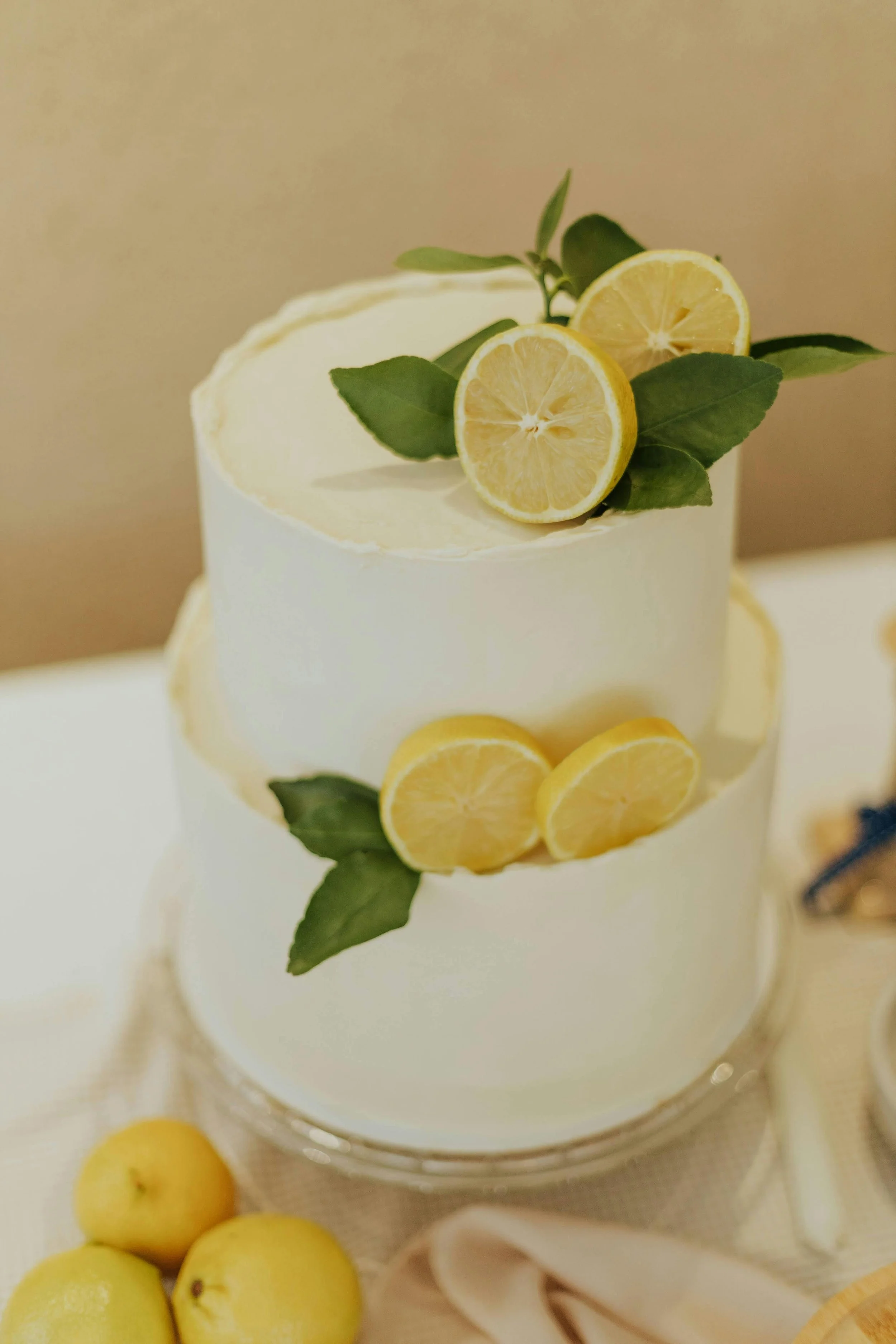 A two-tiered white cake decorated with lemon slices and green leaves.