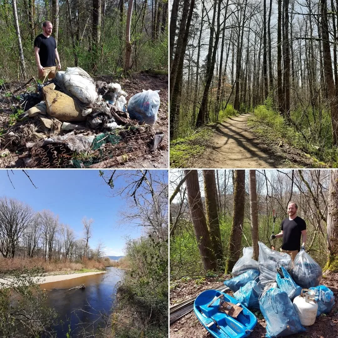 Volunteer removing litter from a forested area near a river, with collected trash bags and cleanup tools, under clear skies.