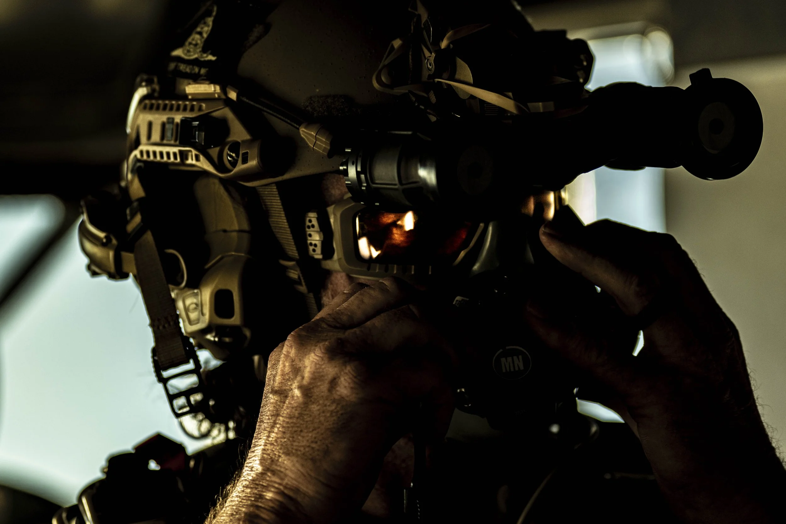 Elderly person aiming a tactical rifle inside a vehicle.