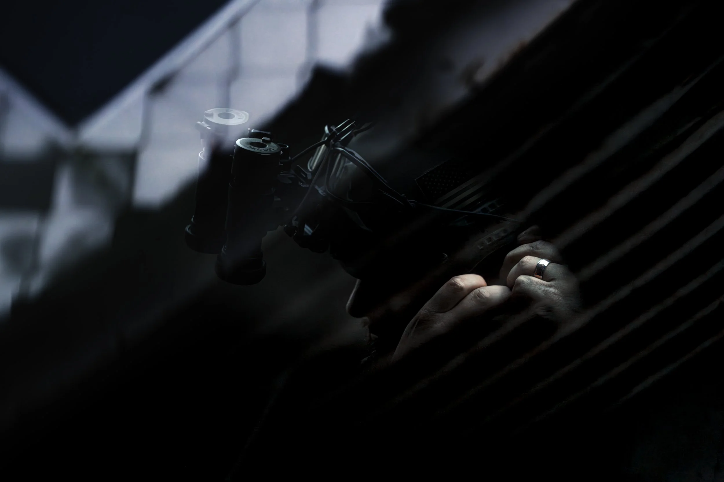 A person with a wedding band on their finger is adjusting or examining the handlebars of a bicycle or motorcycle in a dimly lit space.