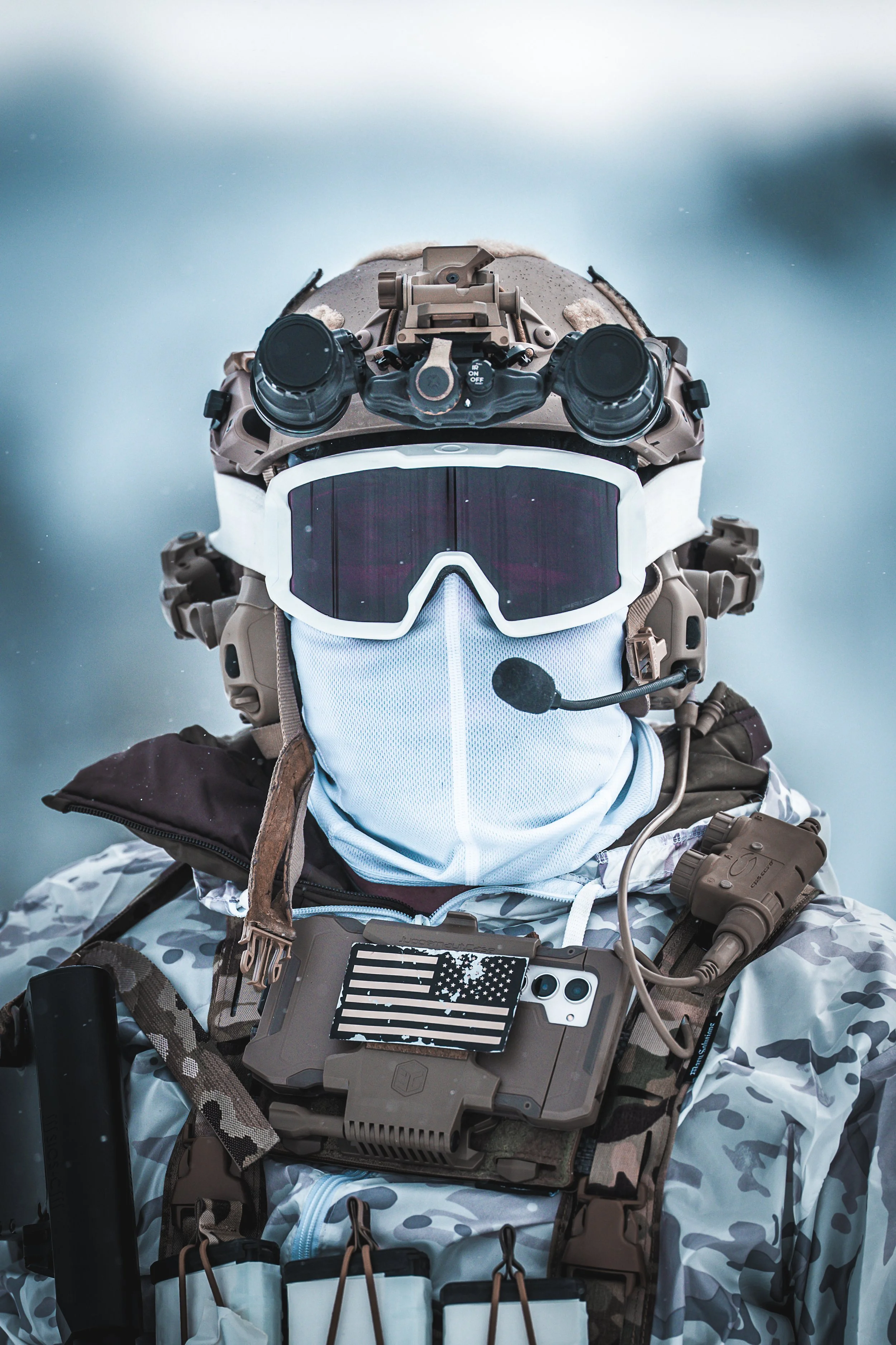 Military personnel in camouflage gear wearing tactical goggles, a headset with microphone, and equipped with communication and navigation devices.