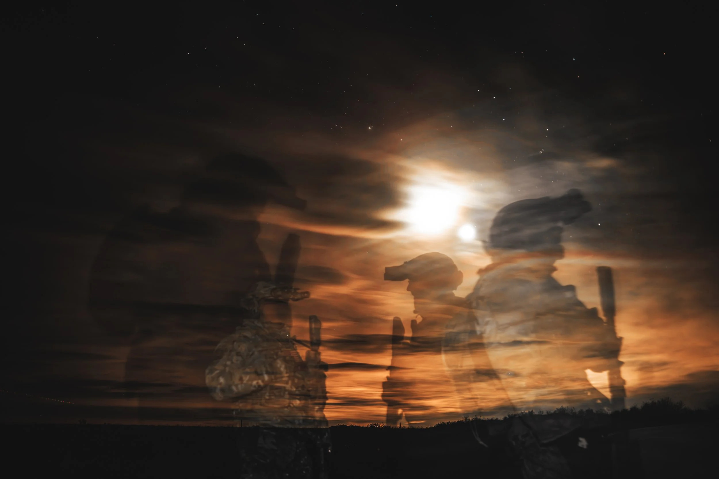 Silhouette of soldiers with helicopters against a sunset sky, with the moon and stars visible.