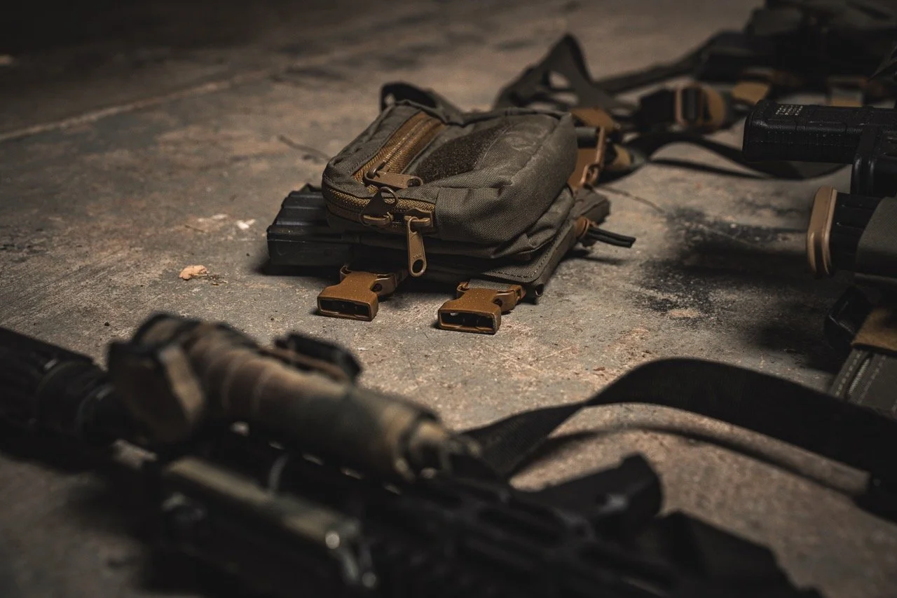 Tactical gear, including a backpack and weapon accessories, spread out on a concrete floor.