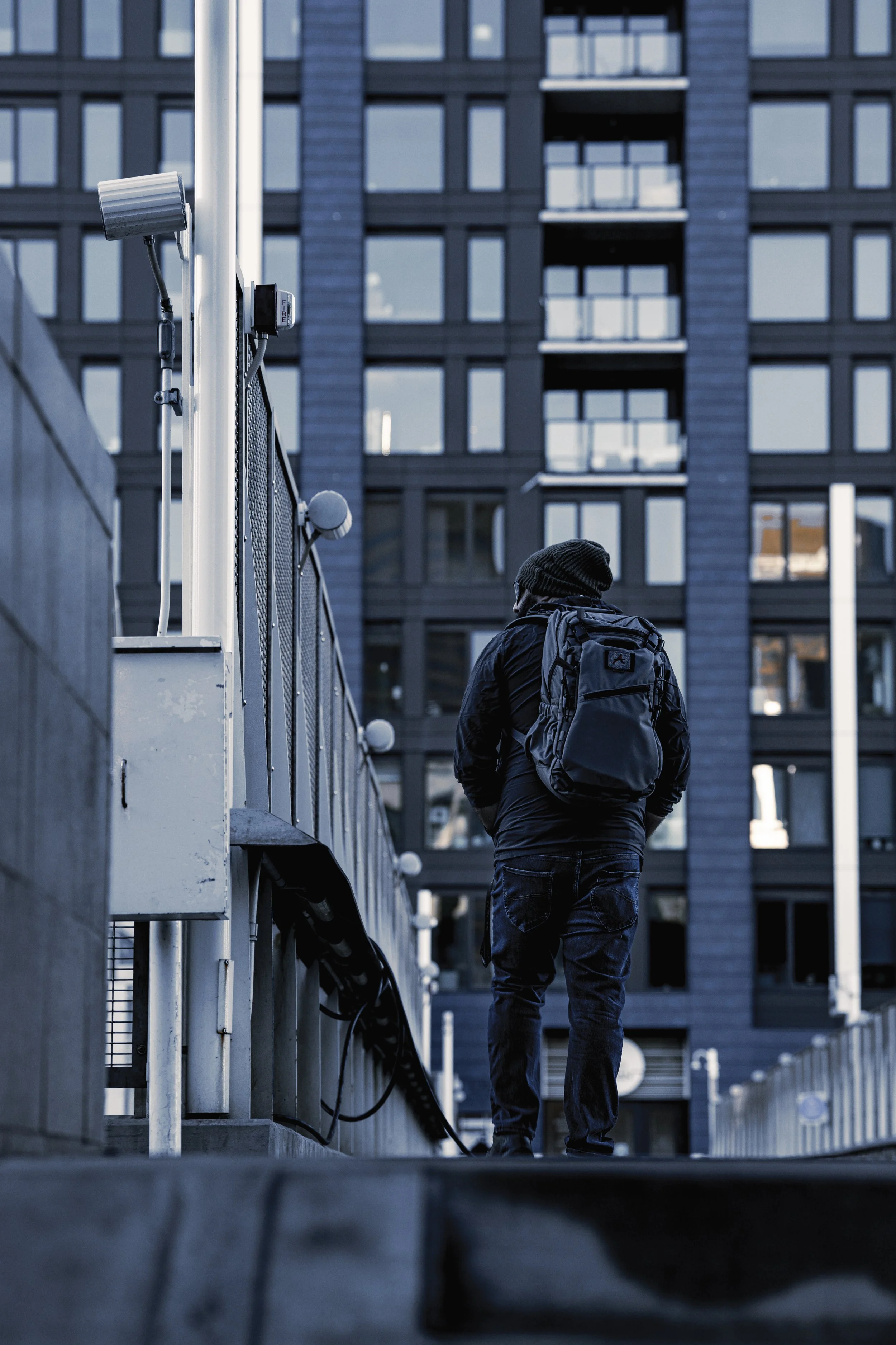 A person with a backpack walking past a tall modern building.