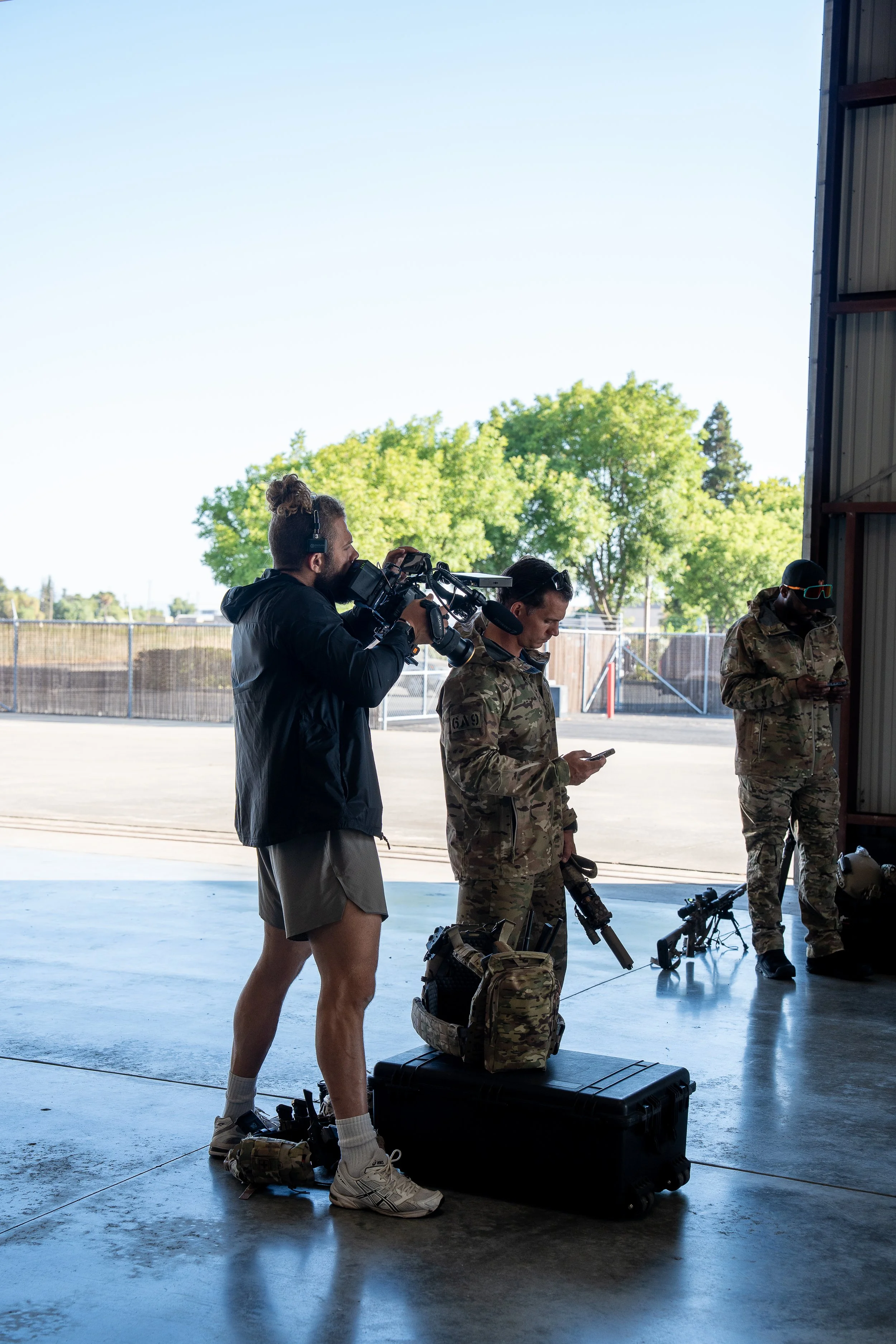 Filming crew capturing footage of soldiers standing in an air hangar.