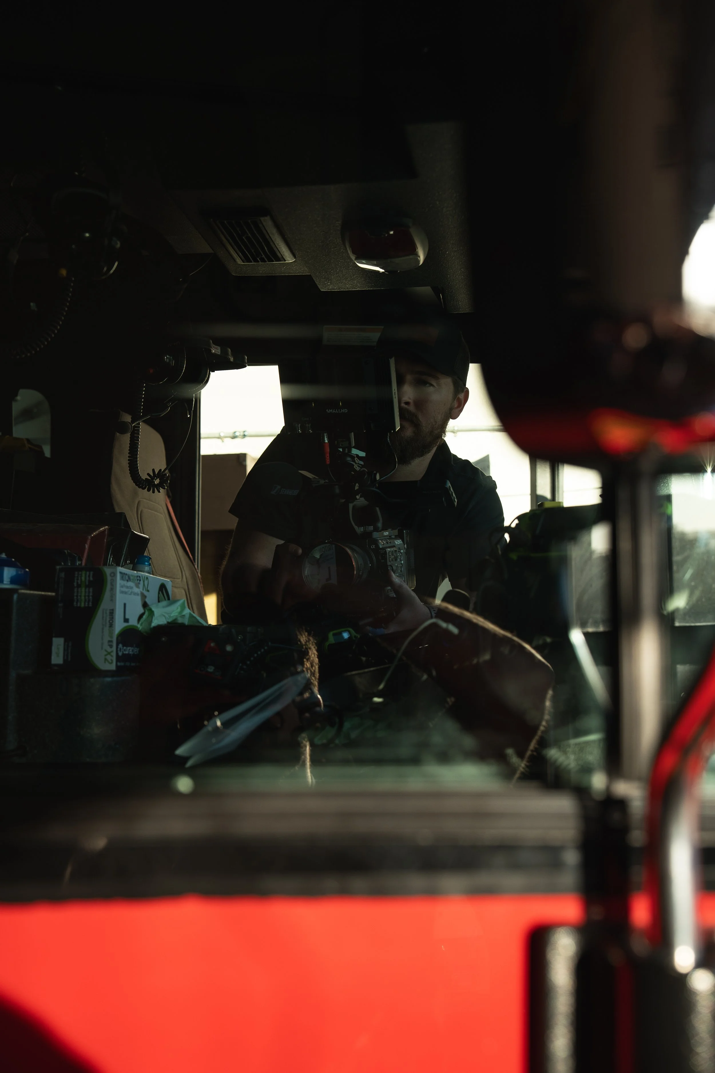 Reflection of a man taking a photo inside a vehicle with various equipment and a red exterior.