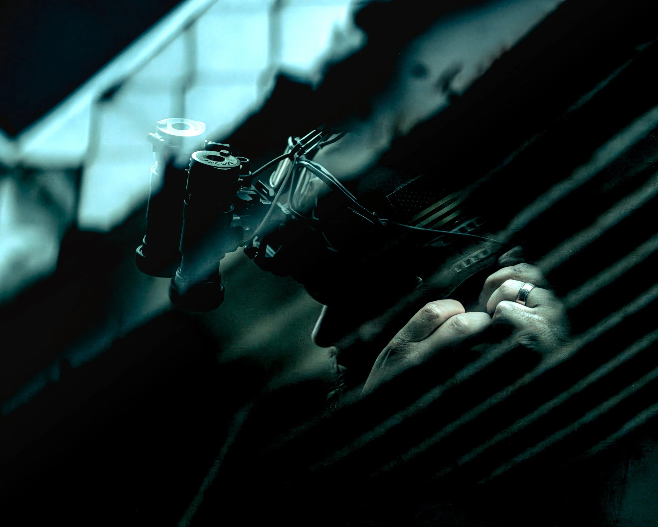 Close-up of a mountain bike with person holding the handlebars behind a glass window with vertical blinds, creating a shadow effect.