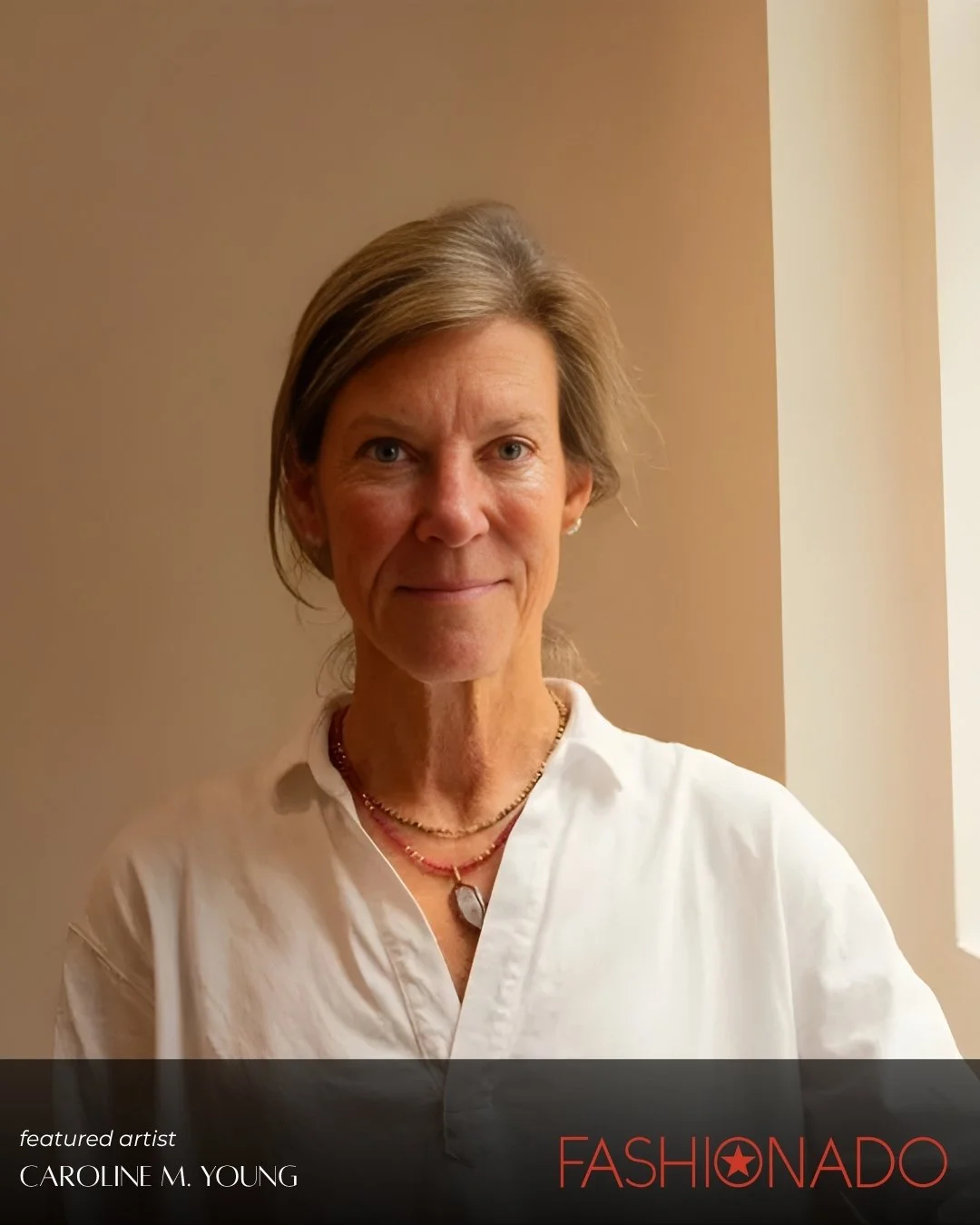Caroline Young is with short, light brown hair, wearing a white shirt and jewelry, standing indoors against a beige wall with a window nearby.