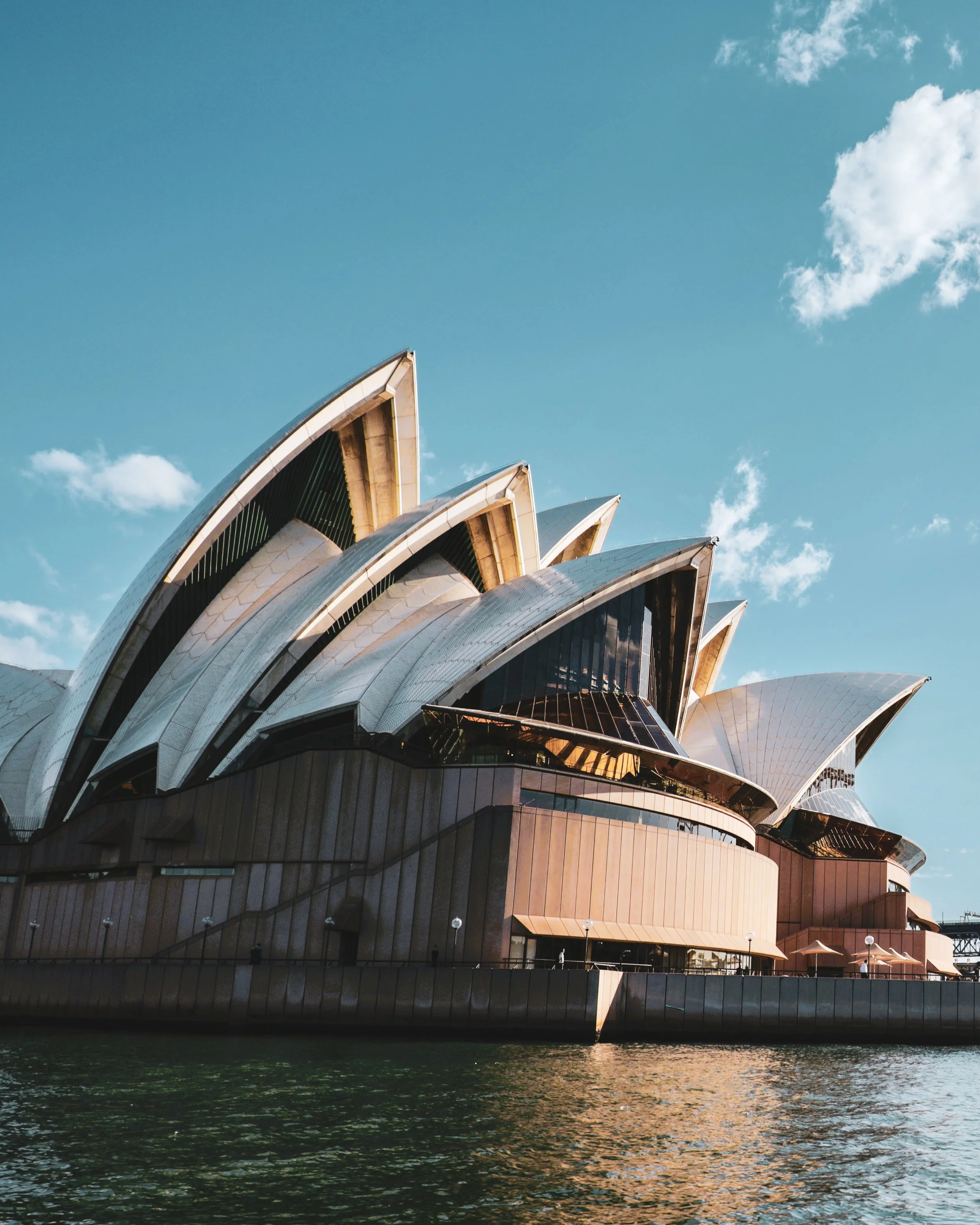 Sydney Opera House with a blue sky and some clouds.