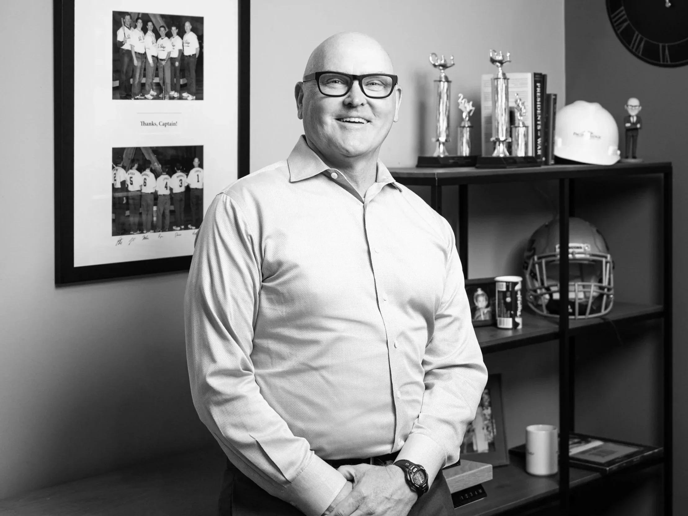 Mark Cooper, a man smiling with trophies on a shelf behind him