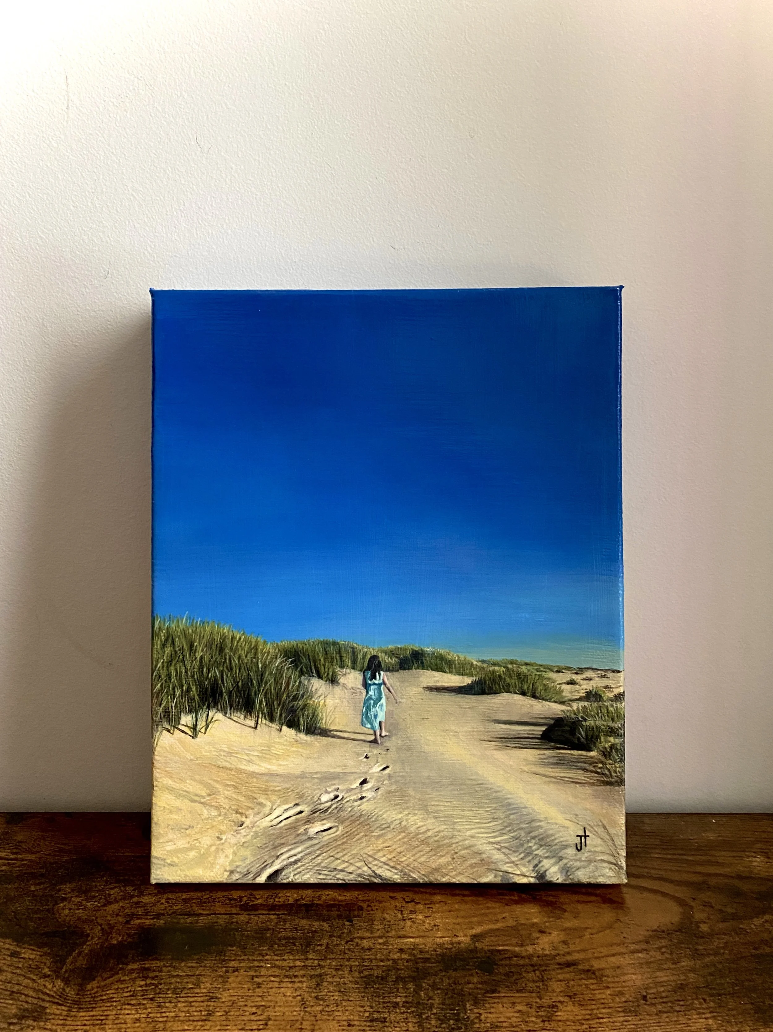 A painting of a woman walking on a sandy beach or dunes towards a bright blue sky, with tall grasses on either side of the path.