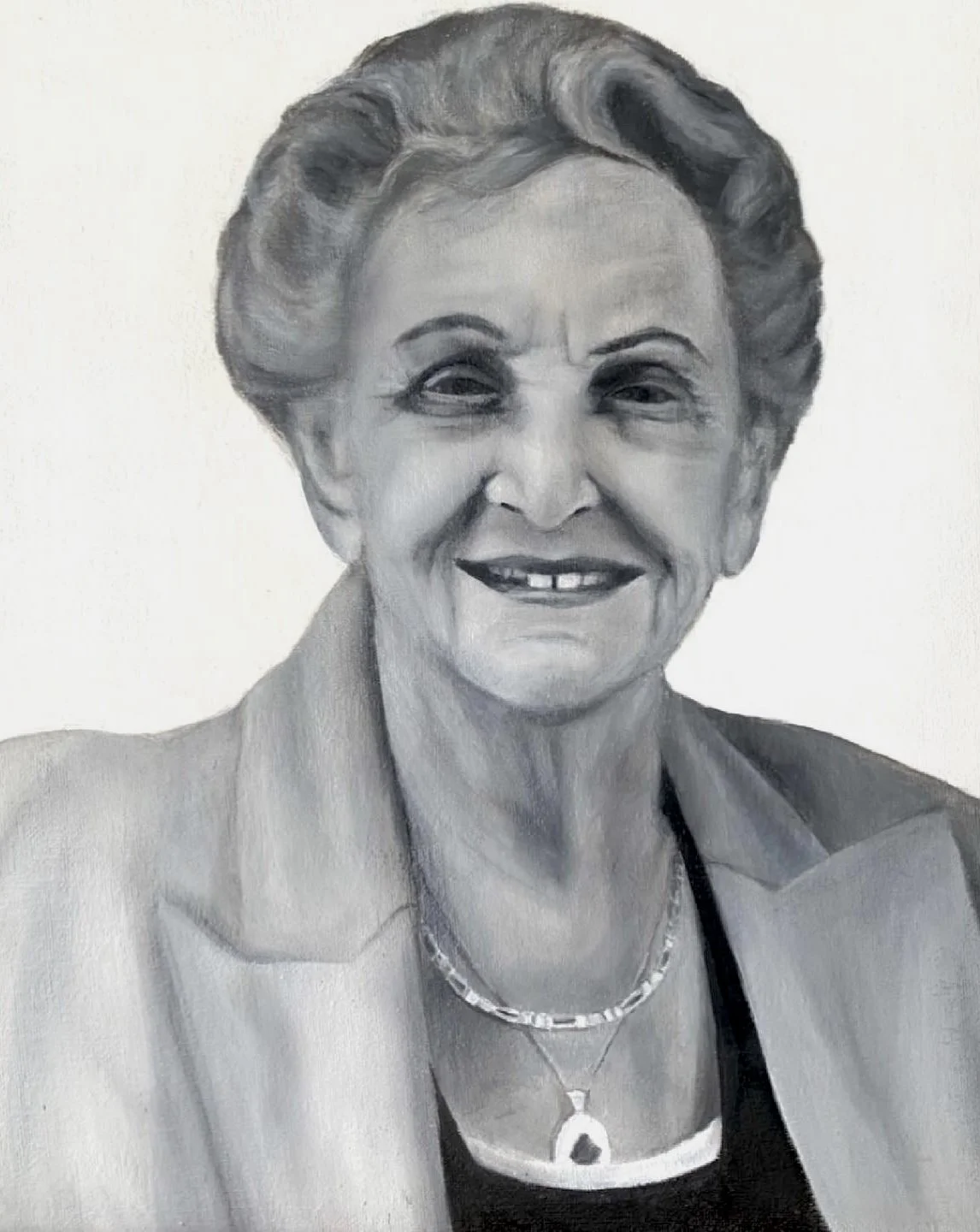 Black and white portrait of an elderly woman with styled hair, wearing a blazer, a necklace, and smiling.