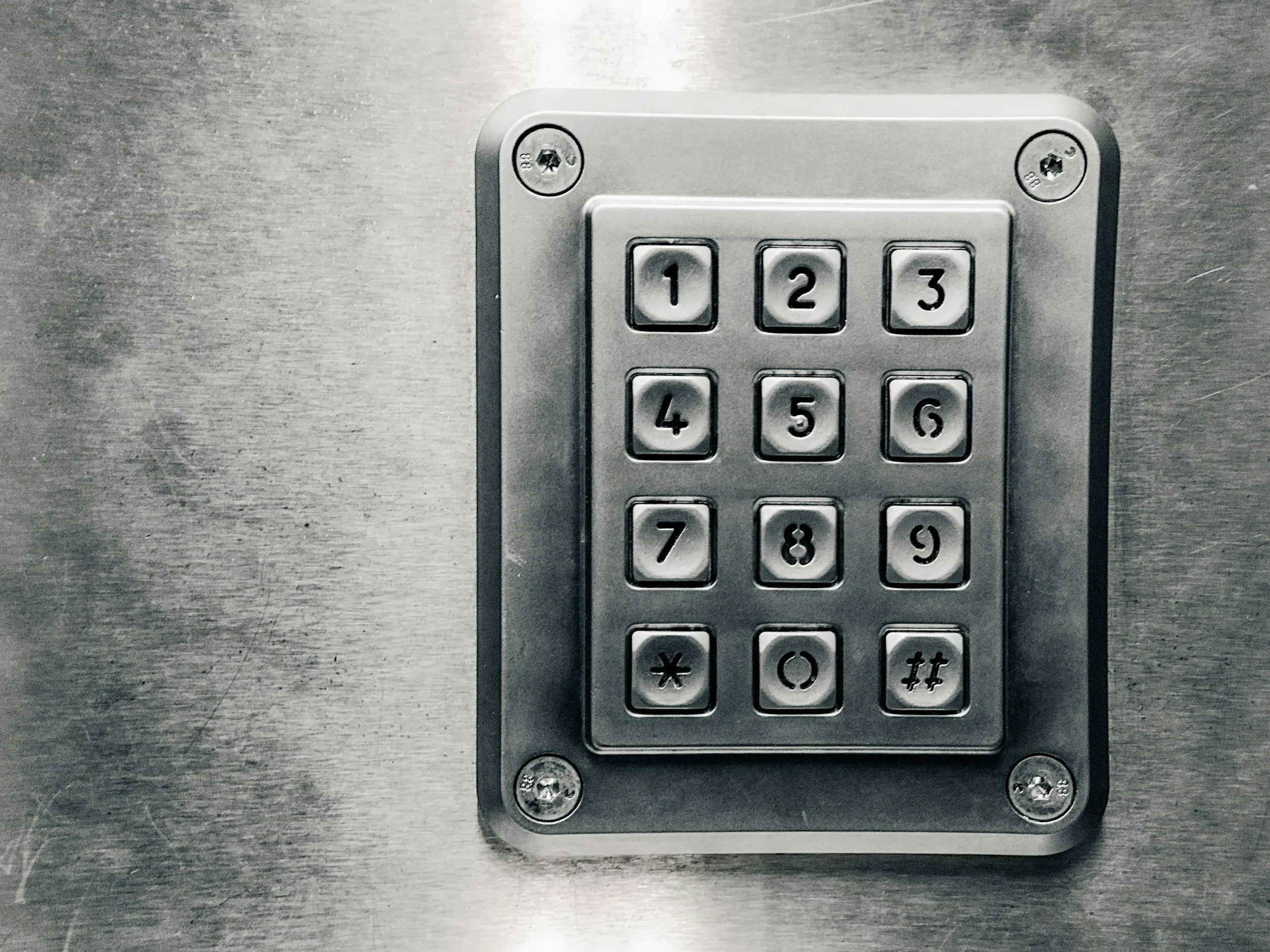 Metal security keypad mounted on a brushed metal surface.
