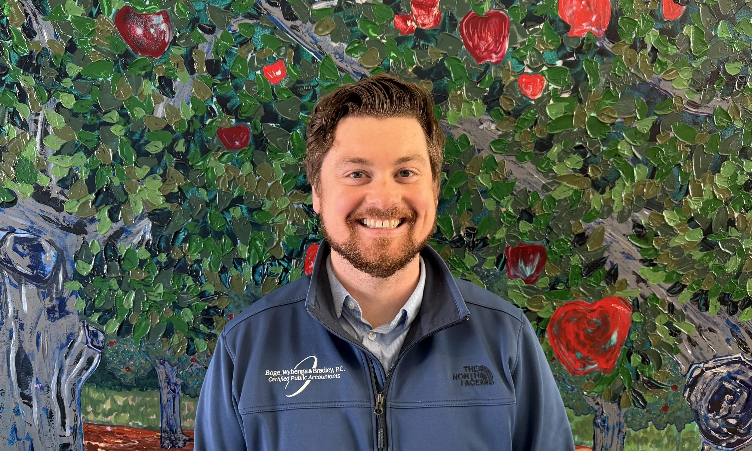 A red and silver striped building with a round tower, stone foundation, and large windows under a clear blue sky.