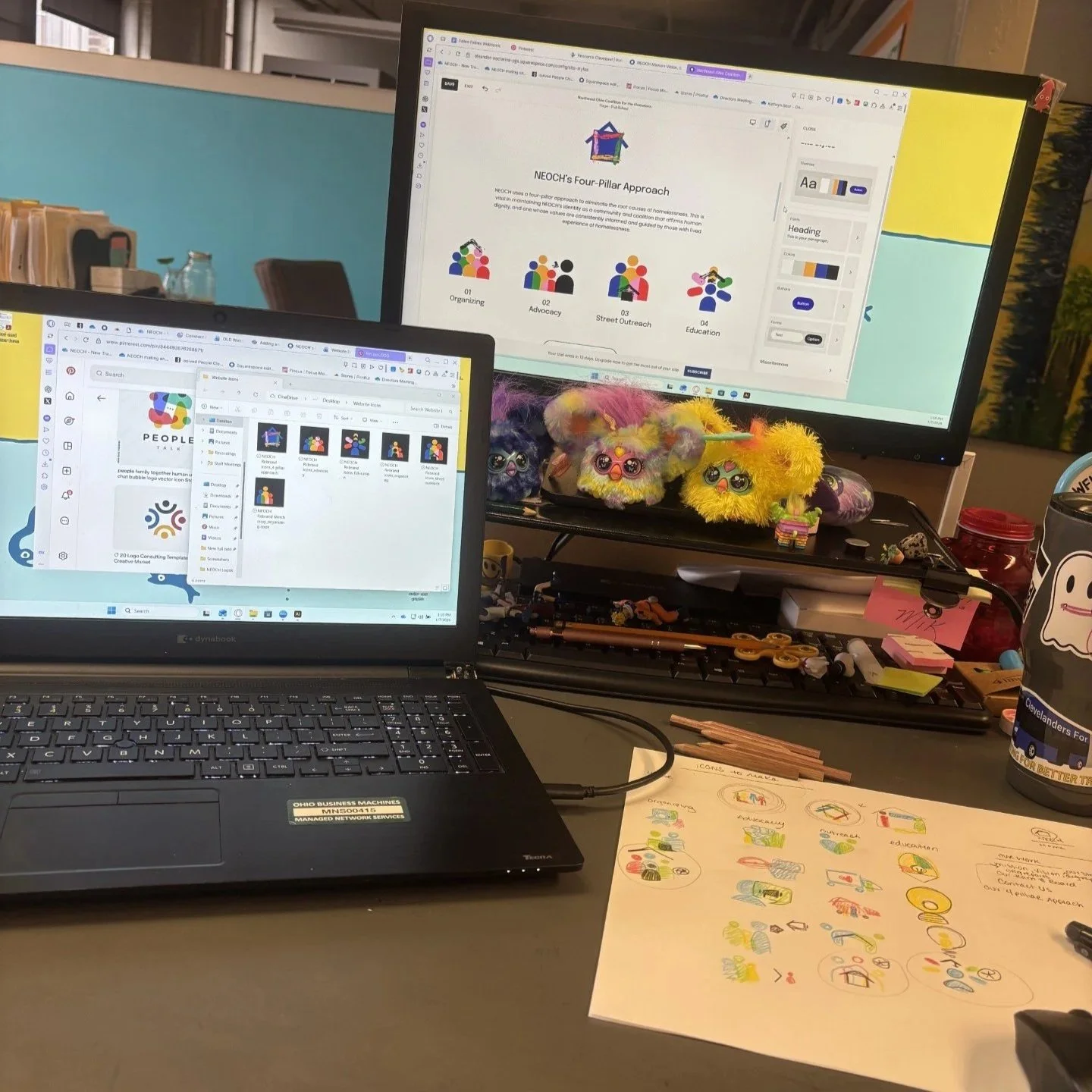Image of a desk with files showing, website editor, and a large piece of paper with hand drawn icons using colored pencil. Some are circled then shown digitized on the laptop screen.