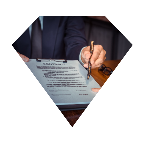 Persona en traje firmando un contrato sobre una mesa de madera.