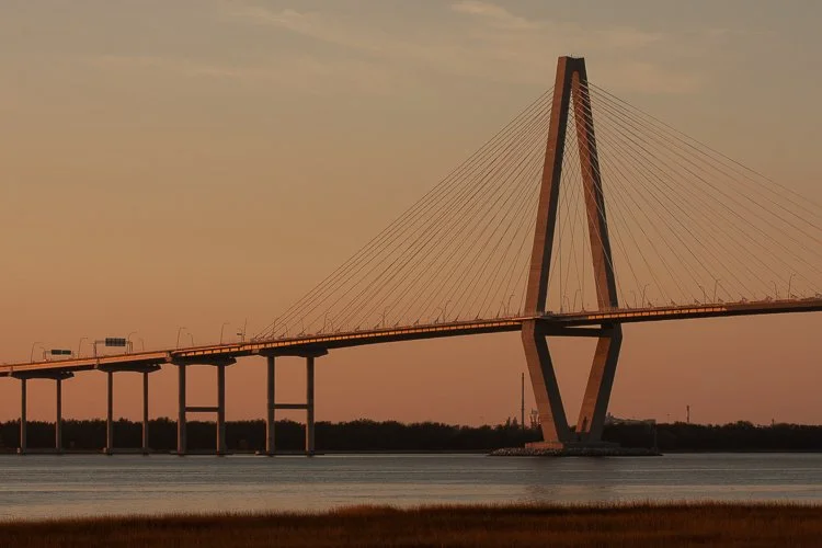 A large cable-stayed bridge crossing a body of water at sunset. Arthur Ravenel Bridge. Photography Classes in Charleston SC. Camera Classes in Charleston SC