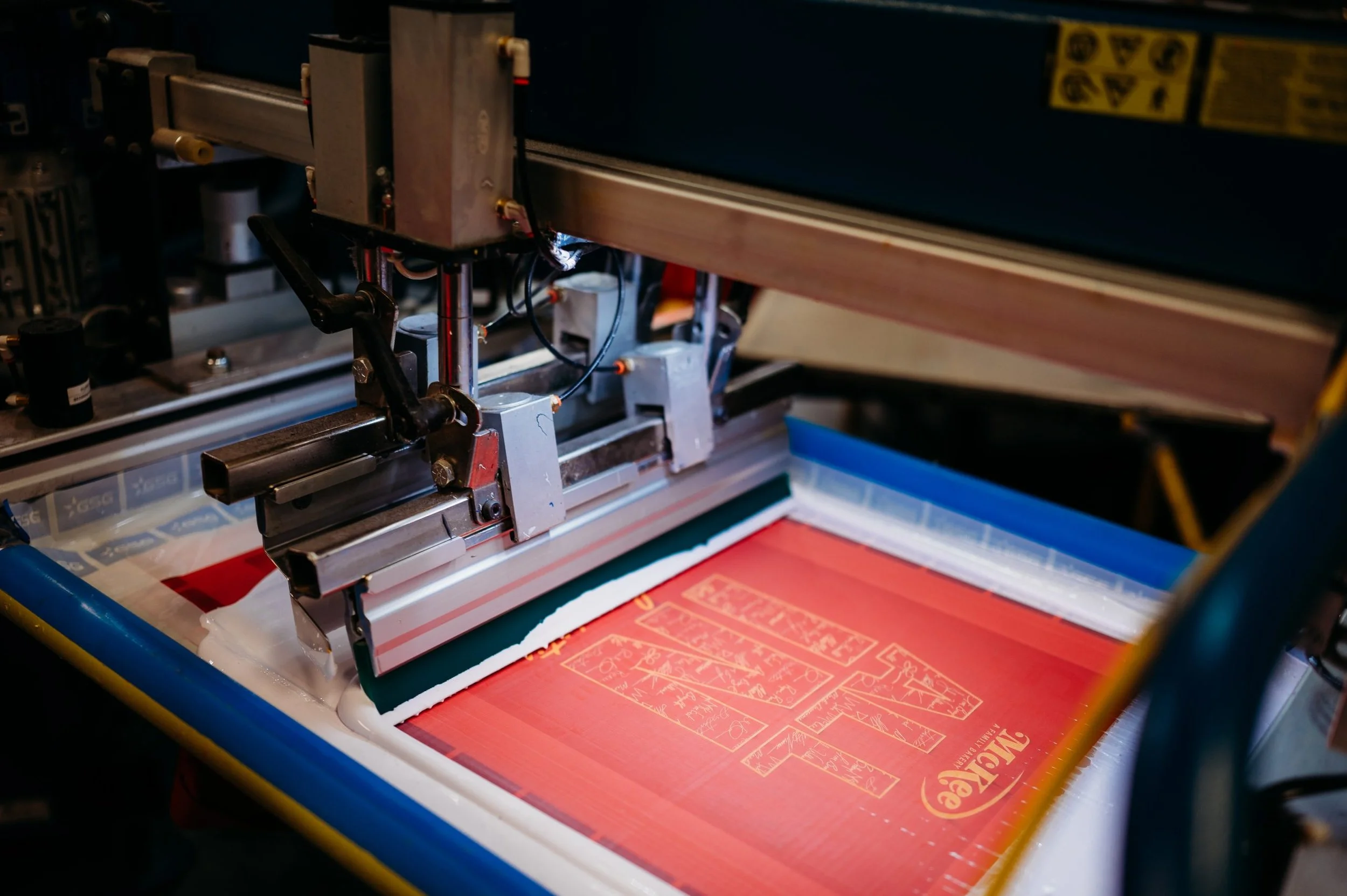 A screen printing machine placing ink onto a t-shirt.