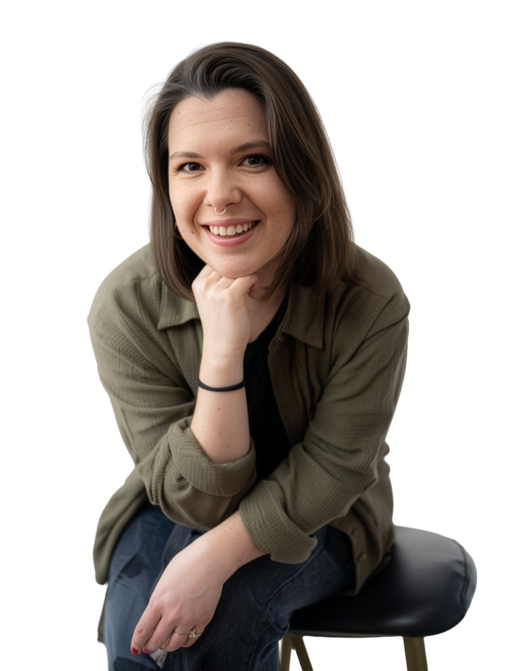 A young woman with shoulder-length brown hair, smiling, sitting on a black stool, wearing a green jacket and black top, with her chin resting on her right hand.