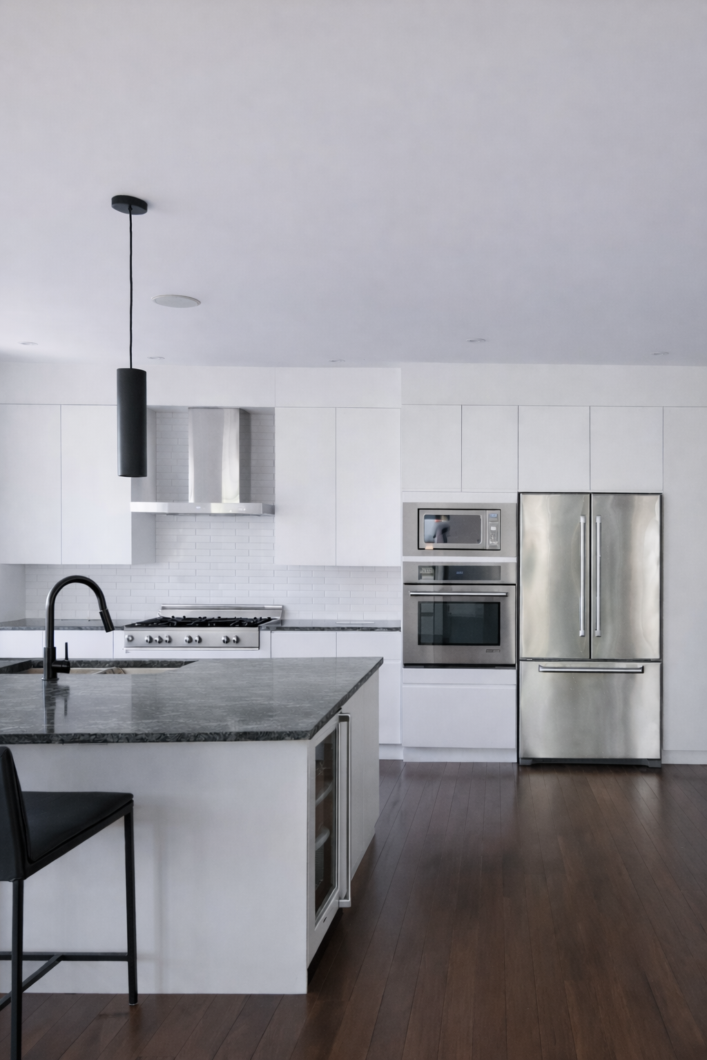 Cuisine moderne avec armoires à prises en J intégrées, comptoirs en quartz et électroménagers en acier inoxydable, pour un espace épuré et fluide.