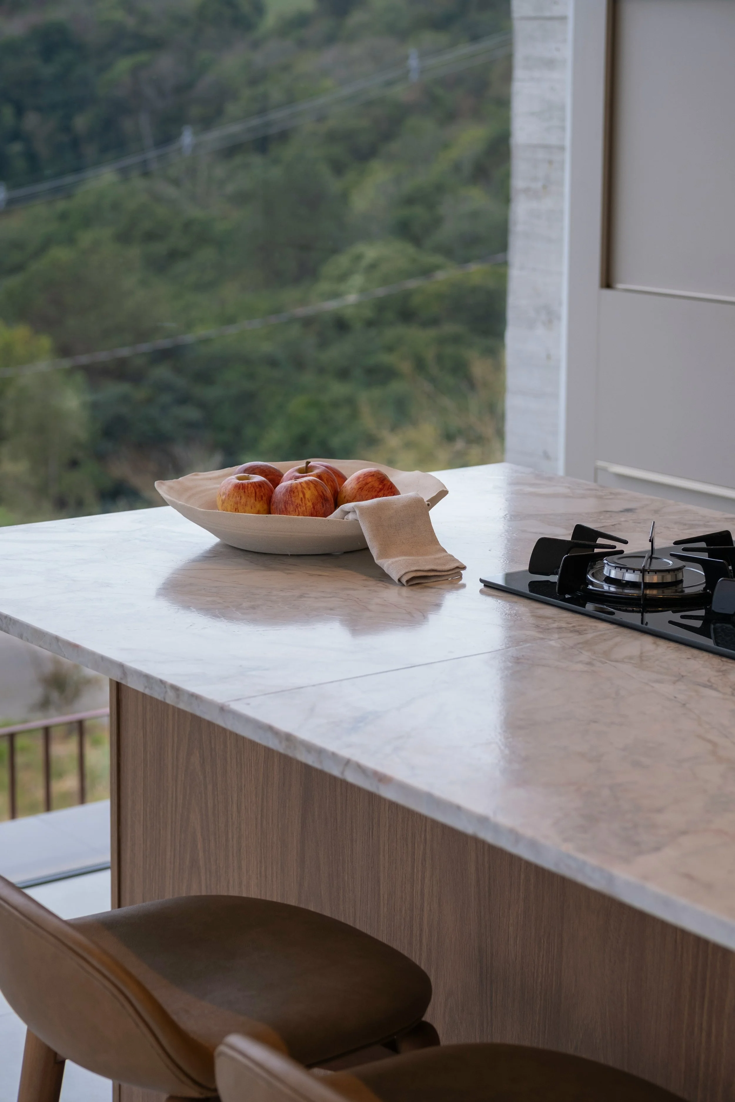 Bright modern white kitchen with slab cabinetry, quartz countertops, marble-look backsplash, and integrated island sink