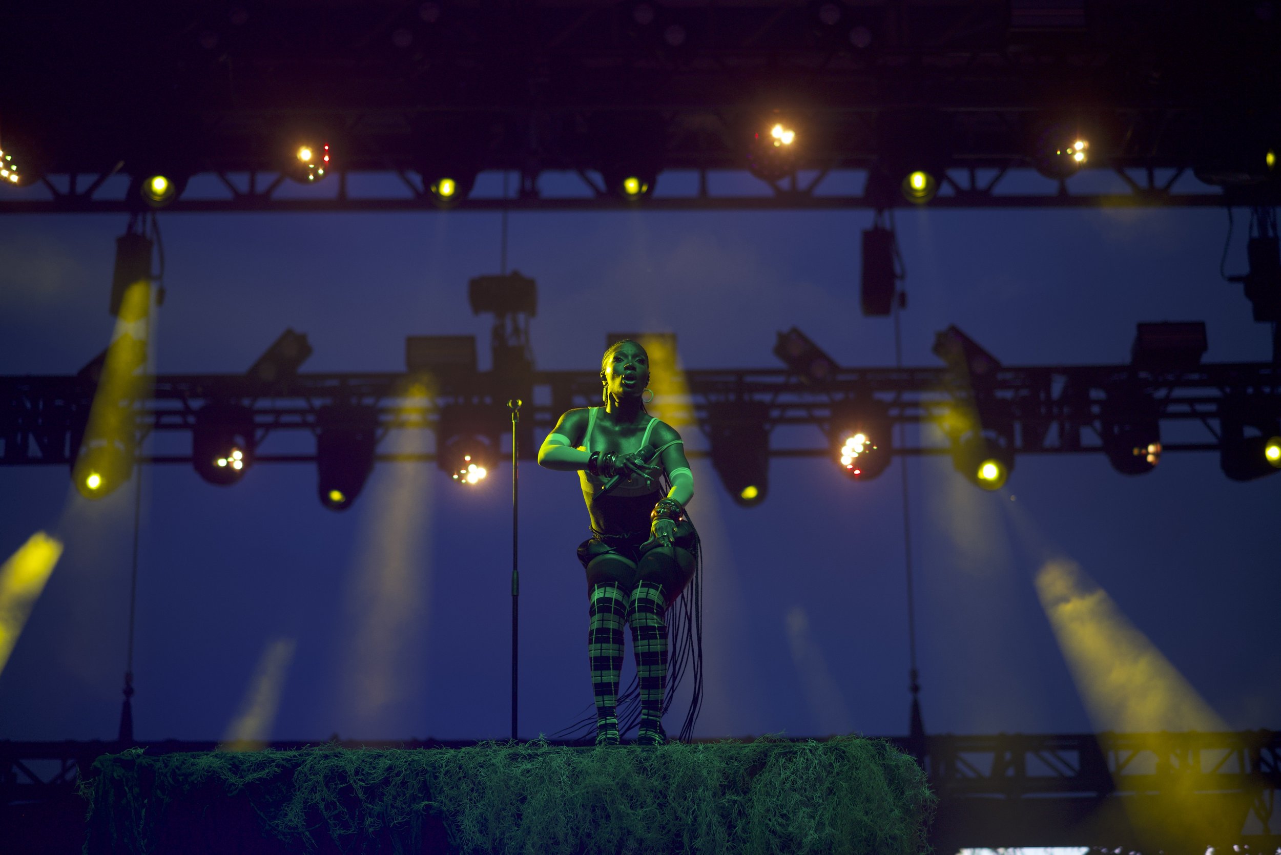 Doechii performing outside on stage with lights illuminating her