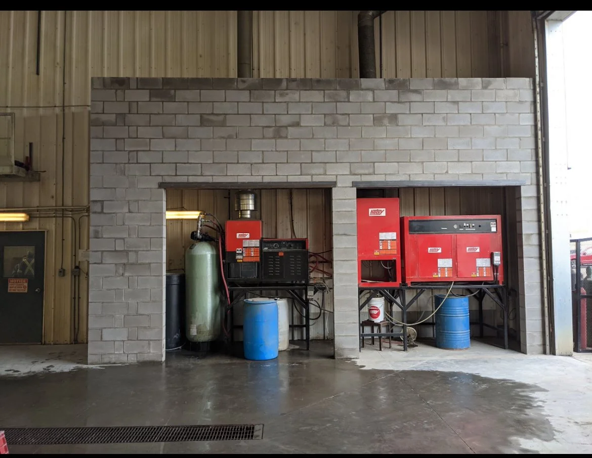 Industrial equipment setup with red machines and blue barrels