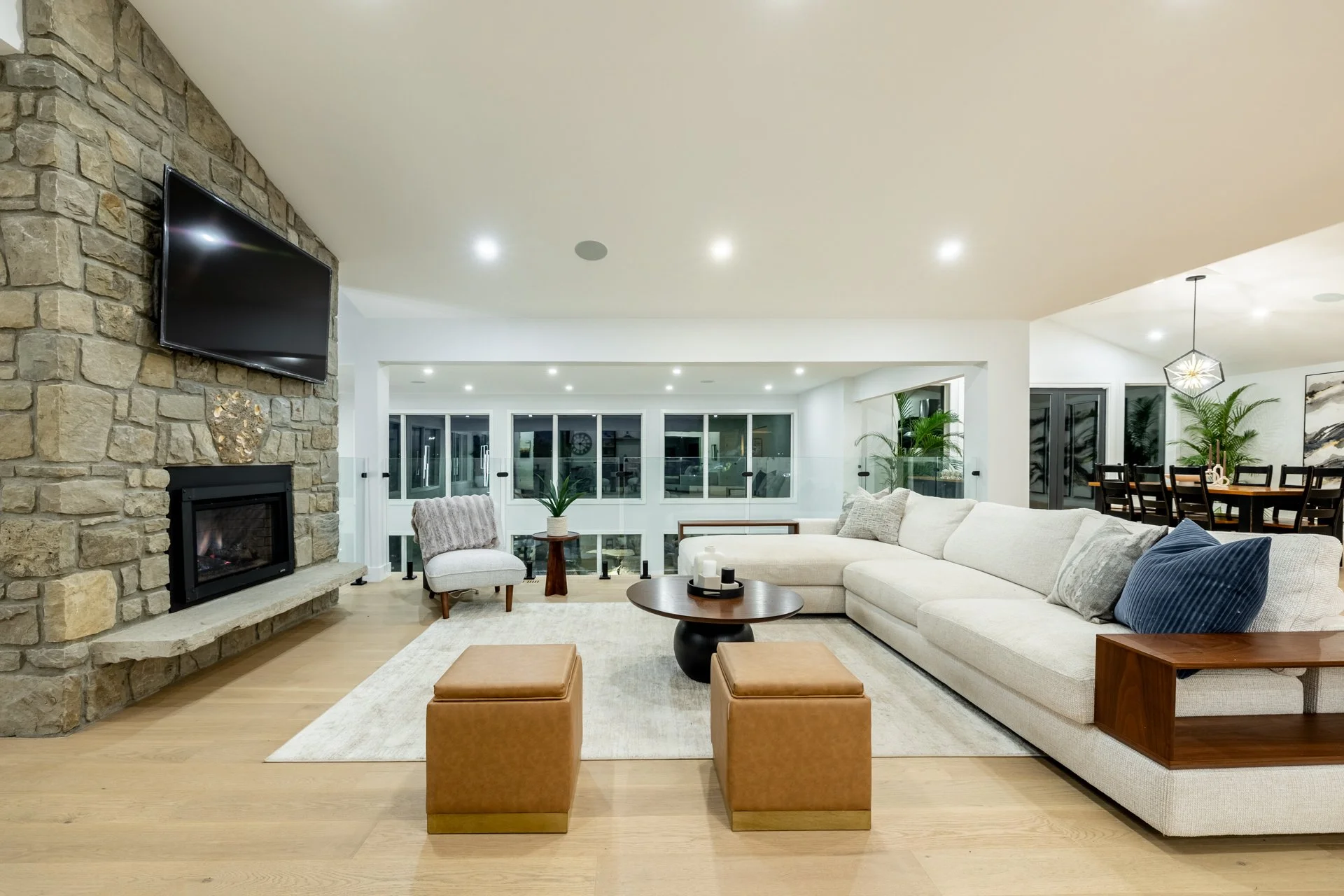 Modern living room with stone fireplace, white sectional sofa, and large windows